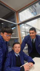 three STC students in blue blazers around a desk
